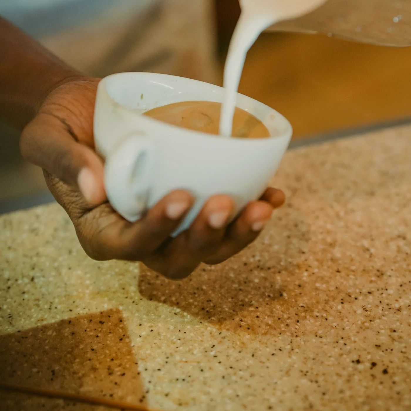 A cup of tea steaming beside a half-played hand of crib on a felt-topped table.